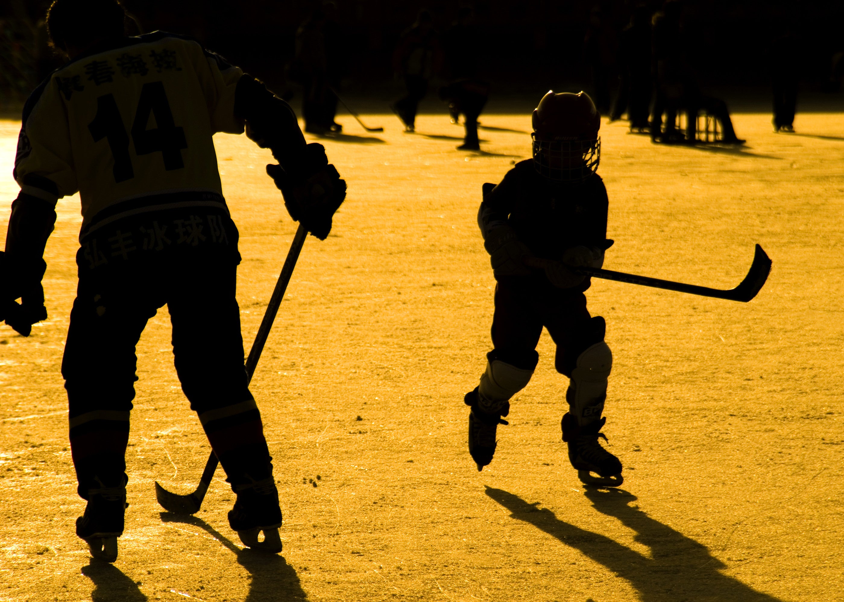 A kid playing hockey at sunset