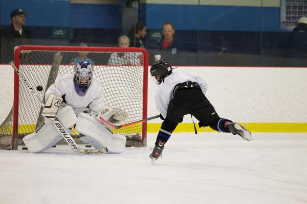 Teenage girl player using dryland pucks with PassMaster on shooting pad and about to shoot towards shooting tarp, while teenage boy player uses stickhandling balls with SweetHands stickhandling aid