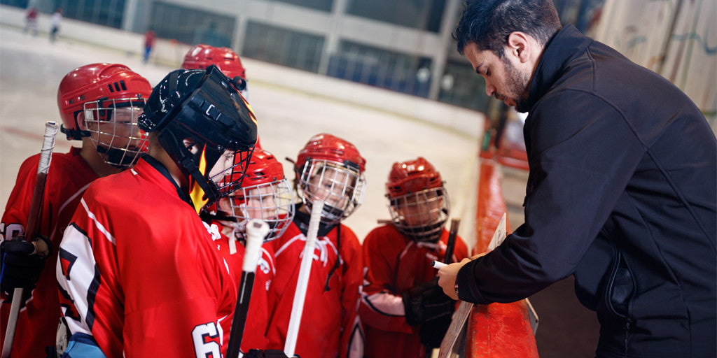 A coach speaking to a group of kids hockey players