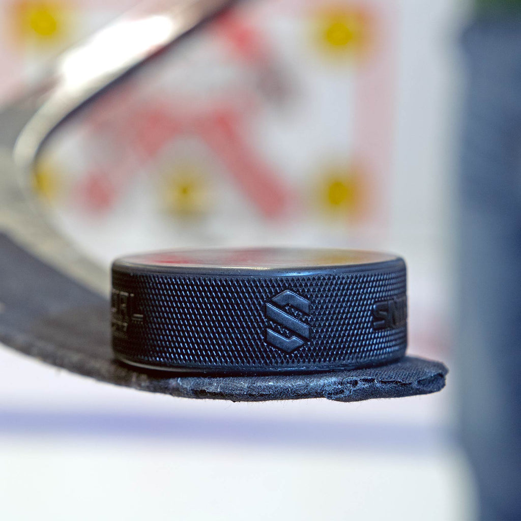 Molded puck resting on hockey stick